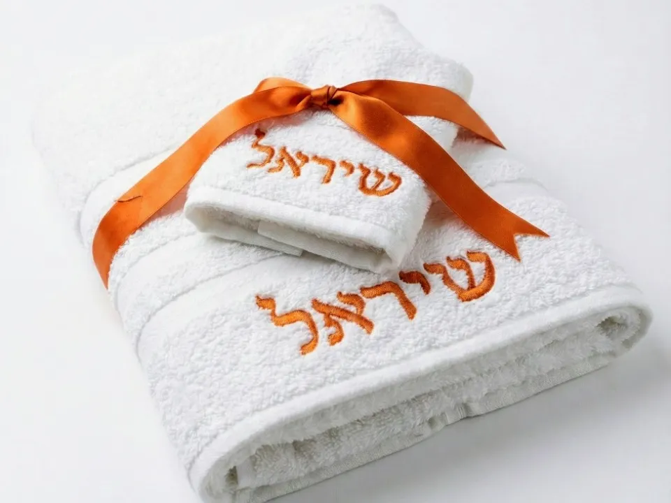 מגבות לבנות עם רקמת שם בצבע כתום וסרט מתנה